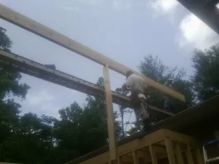 Carpenter setting a ridge beam over a new addition frame — Ice Dam Removal by Roofing Brothers in Richford