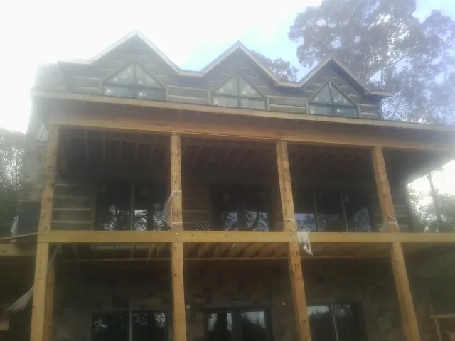 Dormers and porch framing on a large log home under construction — Roof Coating work by our crew in Richford