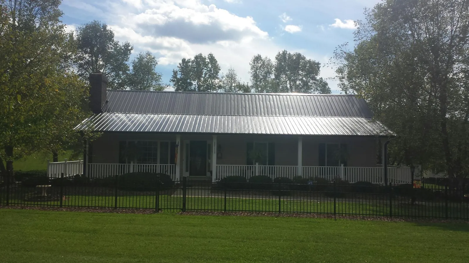 Gray metal roof on a brick ranch with a full width front porch — Gutter Guard Installation work by our crew in Richford