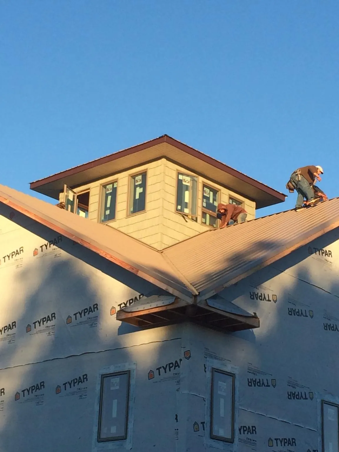 Roofers working around a rooftop cupola on a new metal roof at sunset — Roof Waterproofing in Richford by Roofing Brothers